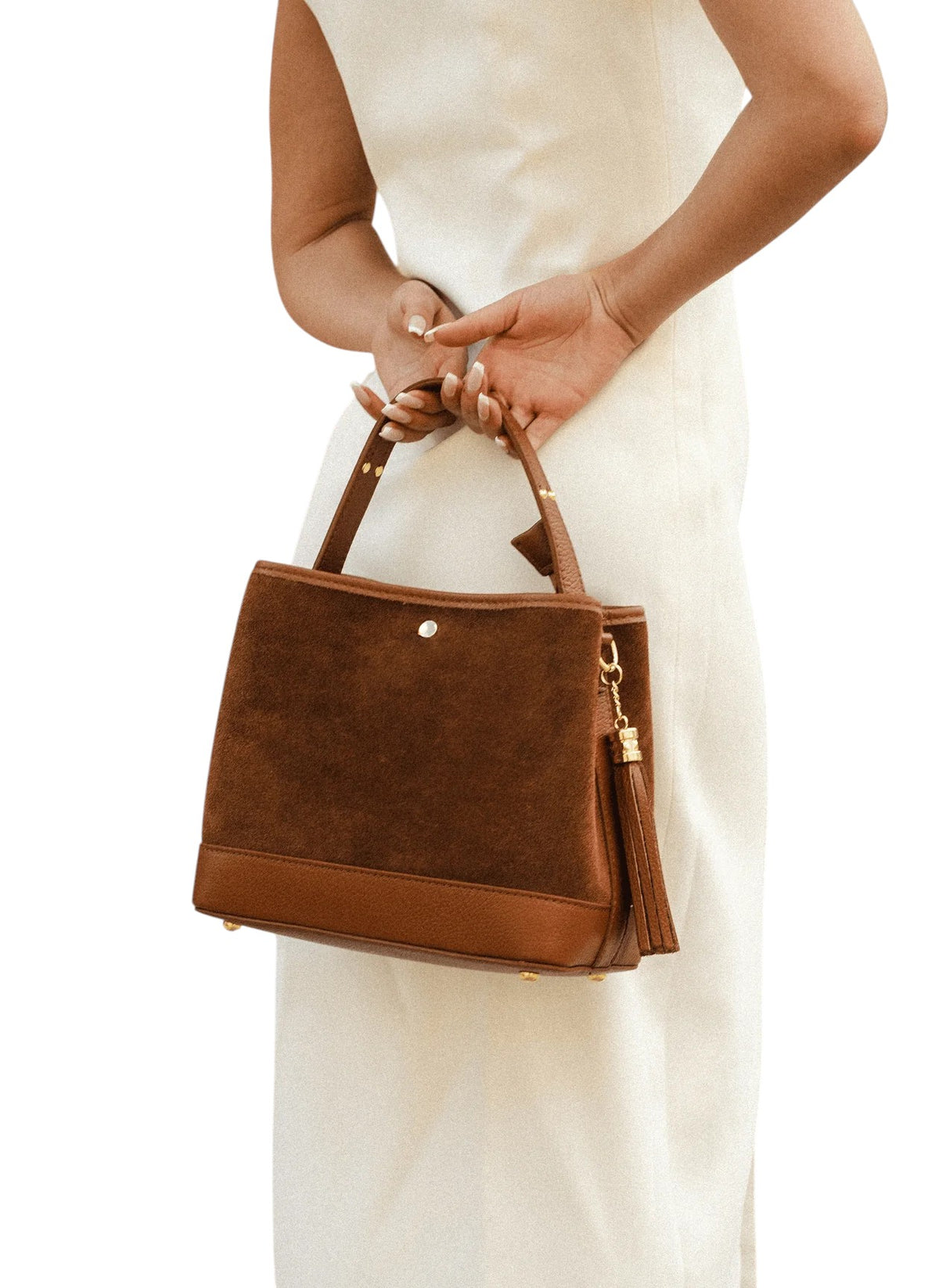 Lala Collection brown suede handbag with smooth leather trim and tassel detail held by a woman in a white dress