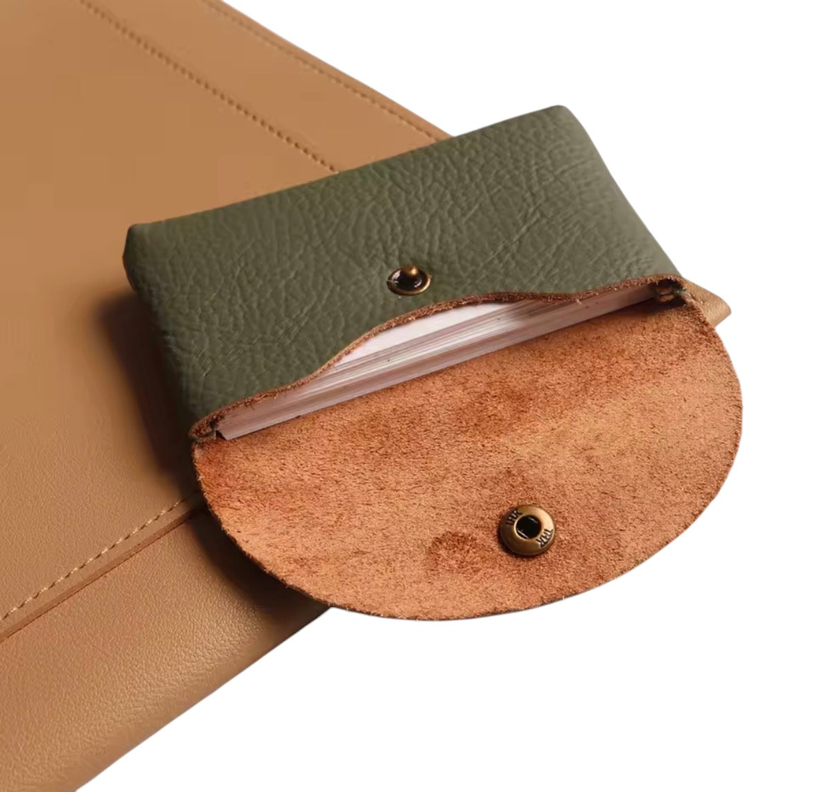 Lala Collection olive green pebbled leather card holder with a snap button closure resting on a tan leather surface